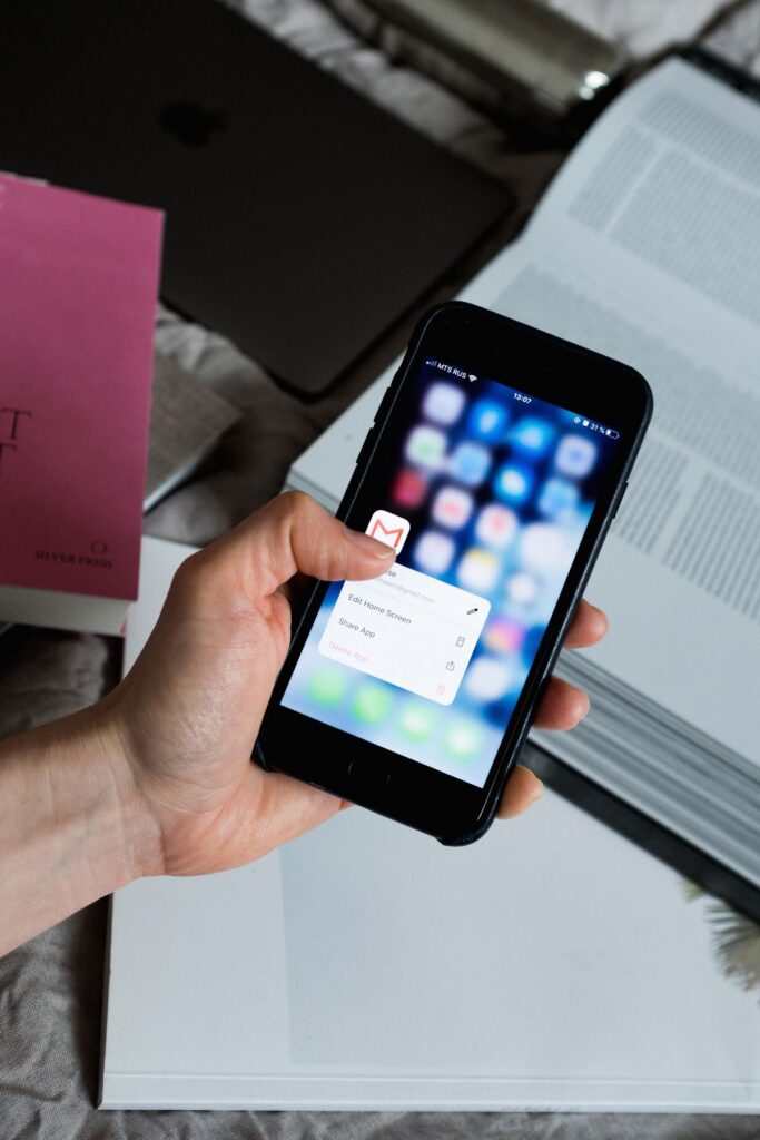 Hand holding a smartphone with an email app open on the inbox screen